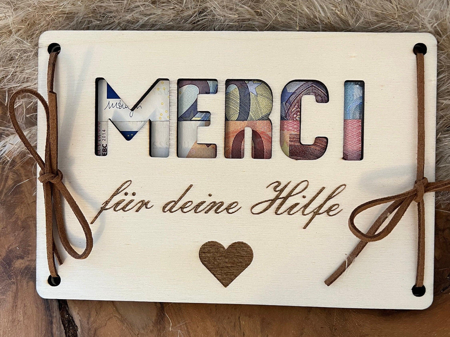 Geldgeschenk: Merci für deine Hilfe. Geldgeschenk aus Holz mit 2 Holzplatten, die obere Platte hat das Wort Merci ausgeschnitten. In der Mitte , der 2 Holzplatten wird das Geld eingelegt. Wobei dann das Geld durchseint.