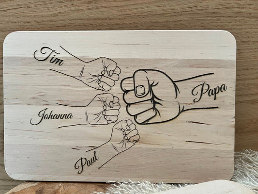 Frühstücksbrettchen personalisiert für Papa. Auf dem Bild ist eine Hand mit Papa draufgraviert, dann Kinderhände mit den Namen der Kinder.