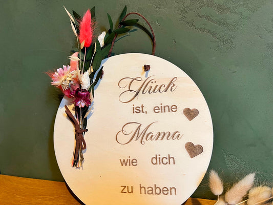 Holzschild graviert mit dem Spruch: Glück ist, eine Mama wie dich zu haben. Dekoriert wird es zusätzlich noch mit Trockenblumen, die dieses Geschenk für Mama abrunden.